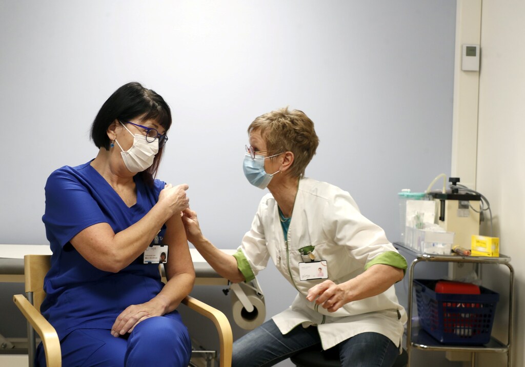 Specialist doctor Mervi Mendiluce receives the Pfizer-BioNTech coronavirus disease (COVID-19) vaccine from nurse Maarit Mukkala at the Tampere University Hospital, in Tampere, Finland, December 28, 2020.