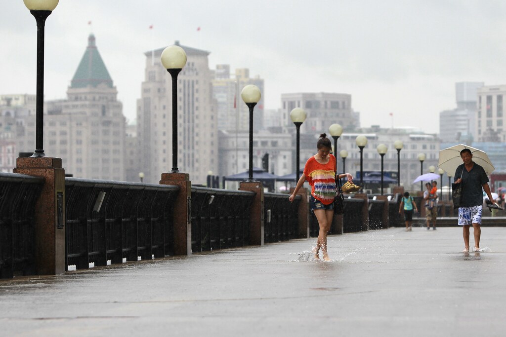 A woman walks along the flooded banks of the Huangpu River, Shanghai.
