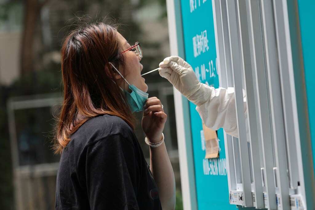 A medical worker takes a swab sample from a person at a mobile nucleic acid testing booth, following the coronavirus disease (COVID-19) outbreak, in Beijing, China June 13, 2022. REUTERS/Tingshu Wang