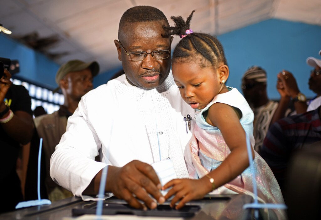 Julius Maada Bio, the presidential candidate for the Sierra Leone People's Party (SLPP), carries his daughter as he casts his vote during a presidential run-off in Freetown, Sierra Leone March 31, 2018. REUTERS/Olivia Acland - RC12F86D4000