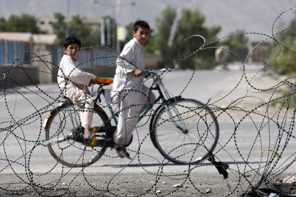 Afghan children ride a bicycle in front of a police station in the center of Kandahar city