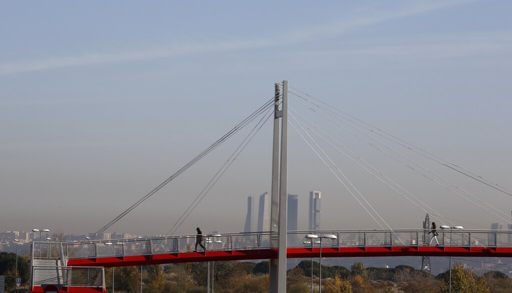 Smog is seen as people walk on a pedestrian bridge in Madrid, Spain, December 3, 2015. The local government of the Spanish capital imposed a speed limit of 70 km/h, down from 90 km/h, in the main bypass of the city in an attempt to control air pollution which has cloaked the city with brown smog for several days. REUTERS/Paul Hanna - RTX1WZVY