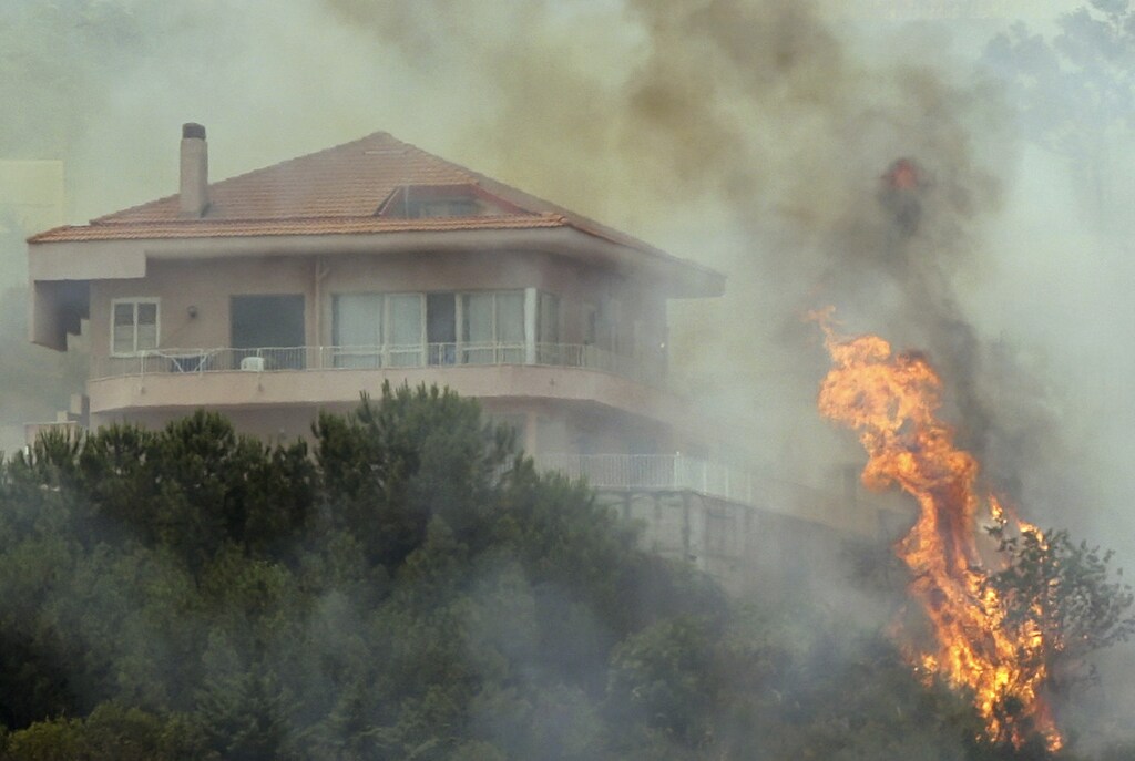 Flames from a forest fire climb towards a house outside the Sicilian capital of Palermo June 26, 2007. Summer temperatures in Europe are likely to be above average this year, while northern parts will probably be wetter than normal and southern regions drier, Britain's leading forecaster said. The house was not destroyed