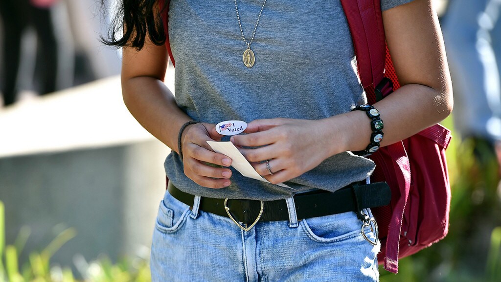 A student holds an "I Voted" sticker as she leaves a polling station on the campus of the University of California, on Irvine, November 6, 2018 in Irvine, California on election day. - Americans vote Tuesday in critical midterm elections that mark the first major voter test of Donald Trump's presidency, with control of Congress at stake. (Photo by Robyn Beck / AFP) (Photo credit should read ROBYN BECK/AFP via Getty Images)