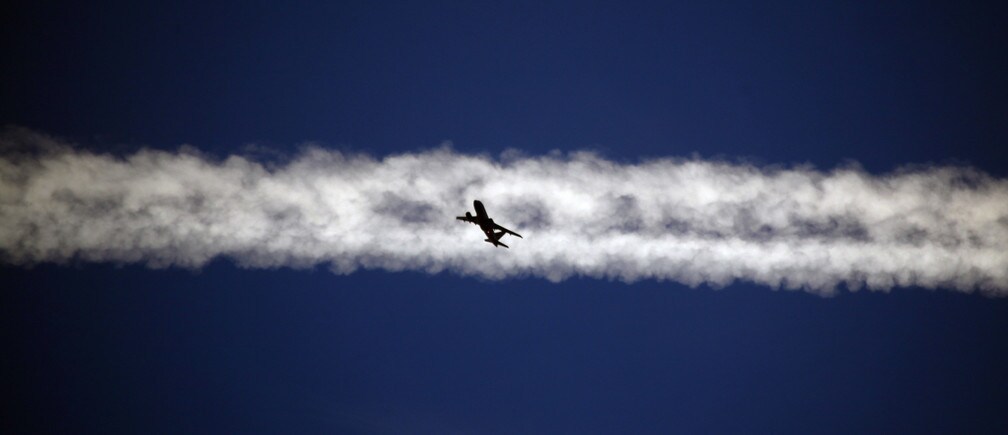An aeroplane flies underneath the jet stream of another aircraft above the Italian city of Padua.