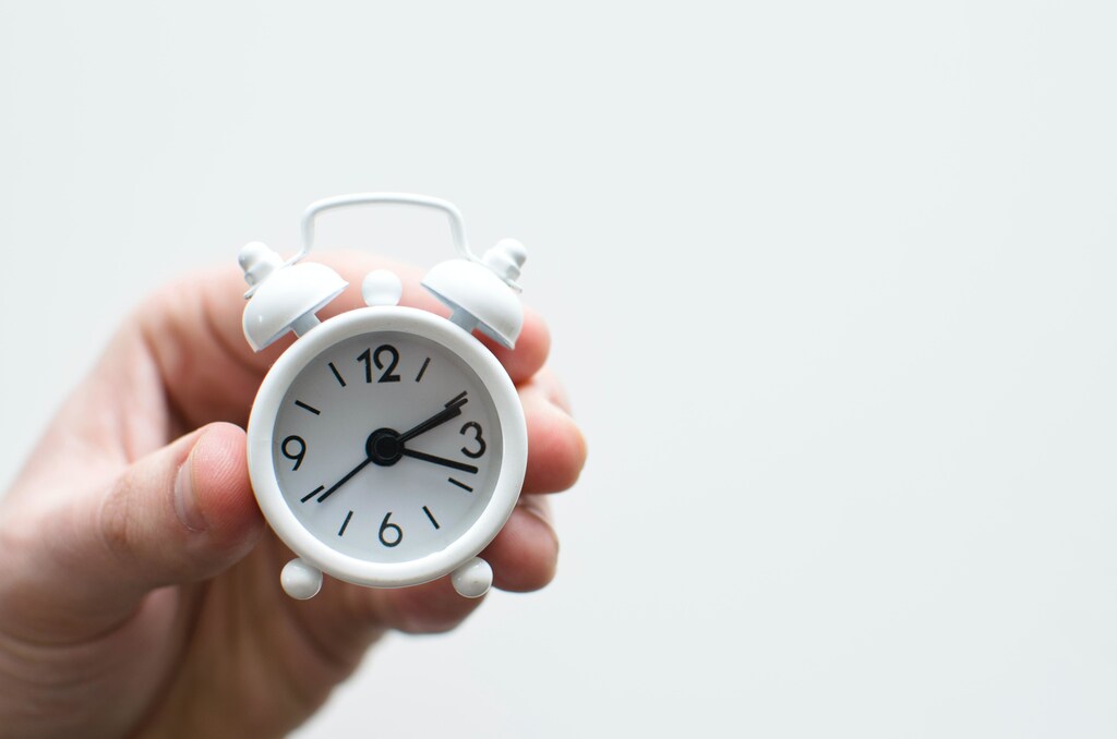 a person holding up a small alarm clock