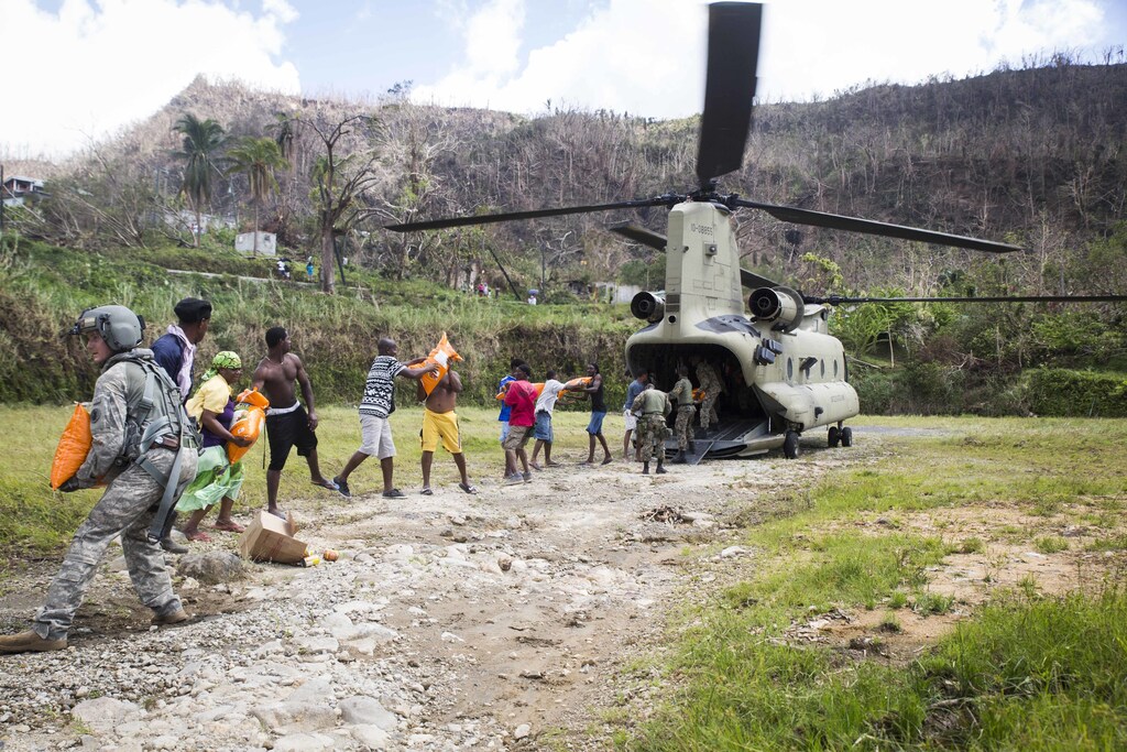 U.S. Army Sgt. Delton Reynolds, left, a flight engineer with Joint Task Force - Leeward Islands, joins a chain with local residents and members of the Jamaican Defence Force to unload relief supplies from a CH-47 Chinook helicopter at Wotten Waven, Dominica, Oct. 3, 2017. The aircraft delivered rice and kitchen sets from the U.S. Agency for International Development to the community. At the request of USAID, JTF-LI has deployed aircraft and service members to assist in delivering relief supplies to Dominica in the aftermath of Hurricane Maria. The task force is a U.S. military unit composed of Marines, Soldiers, Sailors and Airmen, and represents U.S. Southern Commandâs primary response to the hurricanes that have affected the eastern Caribbean. (U.S. Marine Corps photo by Sgt. Ian Leones)