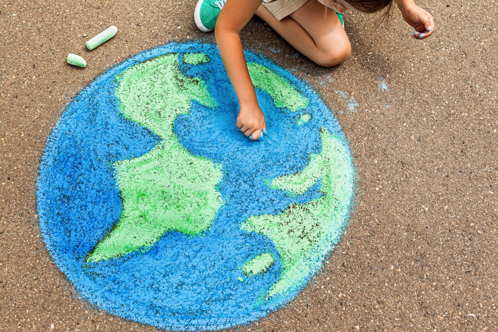 the child girl draws a planet of the world with colored chalk on the asphalt. Children's drawings, paintings and concepts. Education and art, be creative when you return to school. earth, Peace day