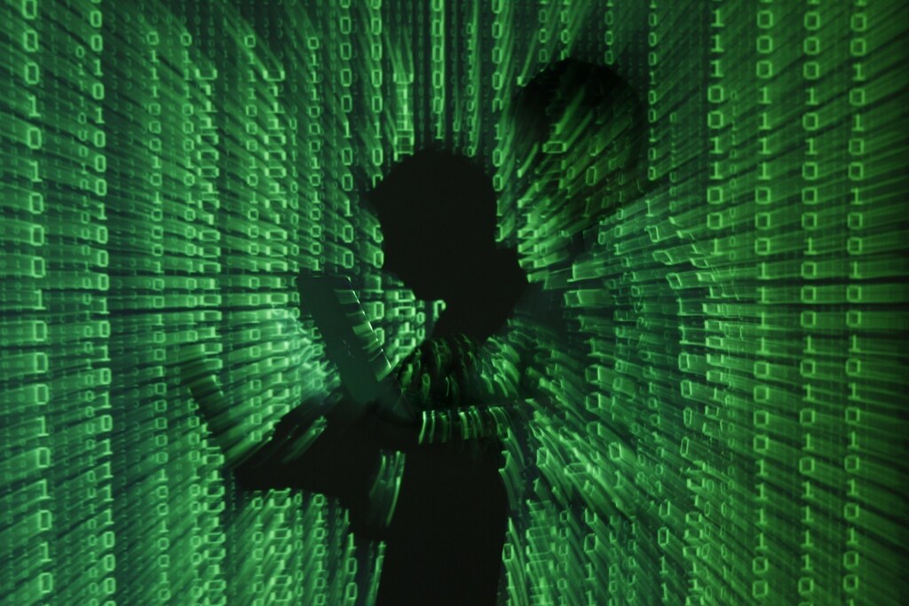 An illustration picture shows a projection of binary code on a man holding a laptop computer, in an office in Warsaw June 24, 2013.