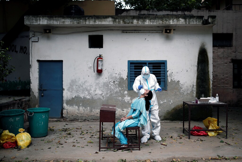A health worker in personal protective equipment (PPE) collects a sample using a swab from a person at a school which was turned into a centre to conduct tests for the coronavirus disease (COVID-19), amidst the spread of the disease, in New Delhi, India, August 6, 2020. REUTERS/Adnan Abidi - RC2A8I9FMIBR