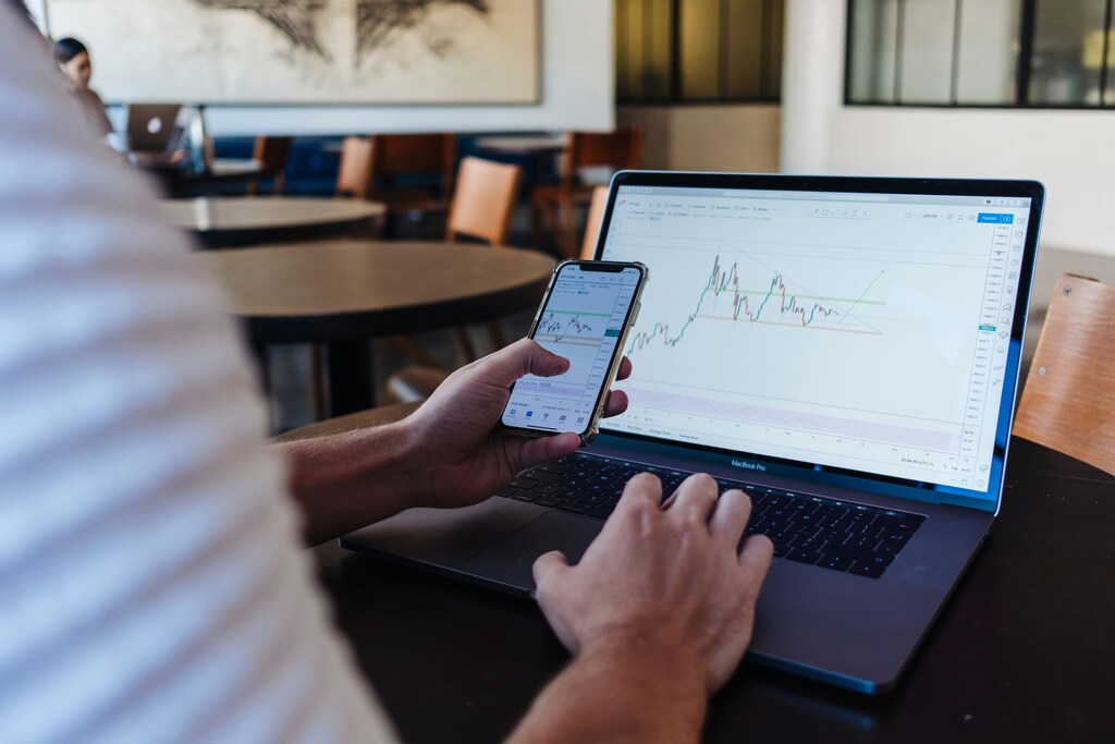 A man looking at stocks on his phone and laptop using AI