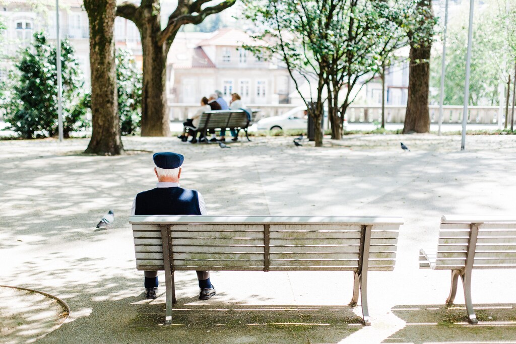 A man sits alone on a bench in a park.