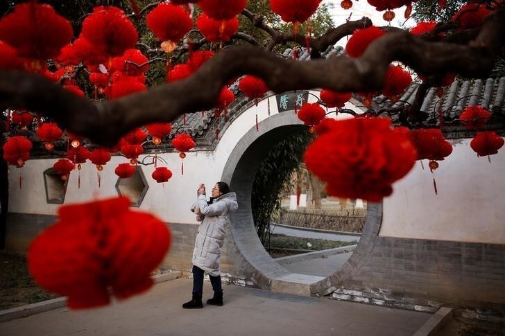 A woman takes pictures of trees decorated for Spring Festival ahead of the Chinese Lunar New Year at Ditan Park in Beijing, China February 11, 2018. REUTERS/Thomas Peter