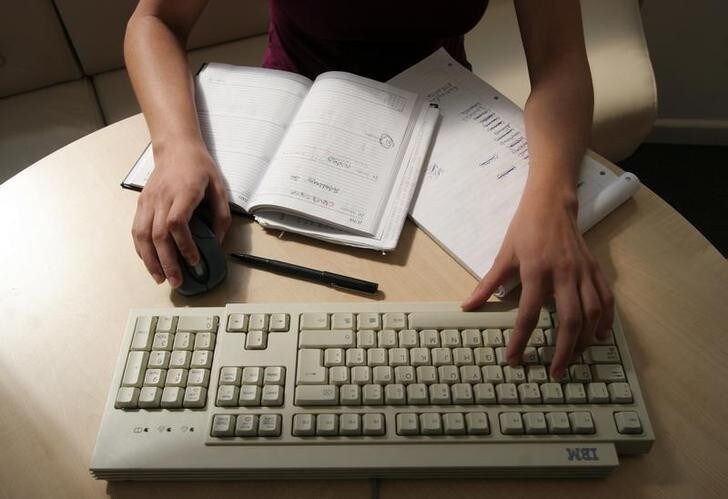 A generic picture of a woman working in an office sitting at her desk typing on a computer. REUTERS/Catherine Benson CRB