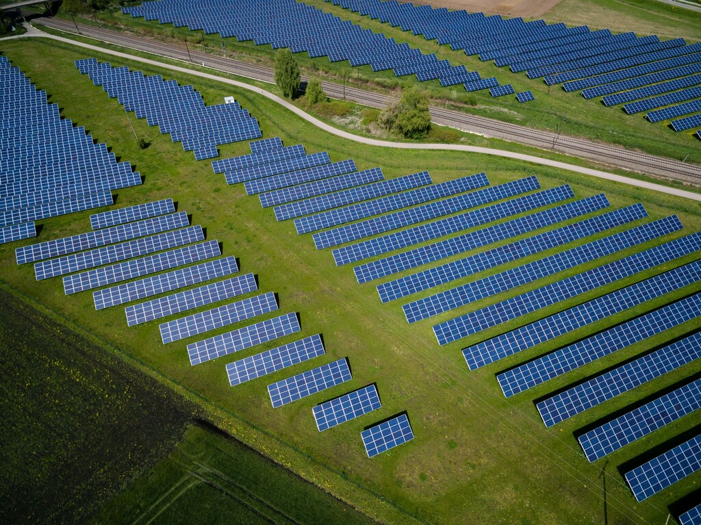 Aerial view of rows of solar panels on a green field: The demand for green skills and clean energy workers has been rising exponentially.