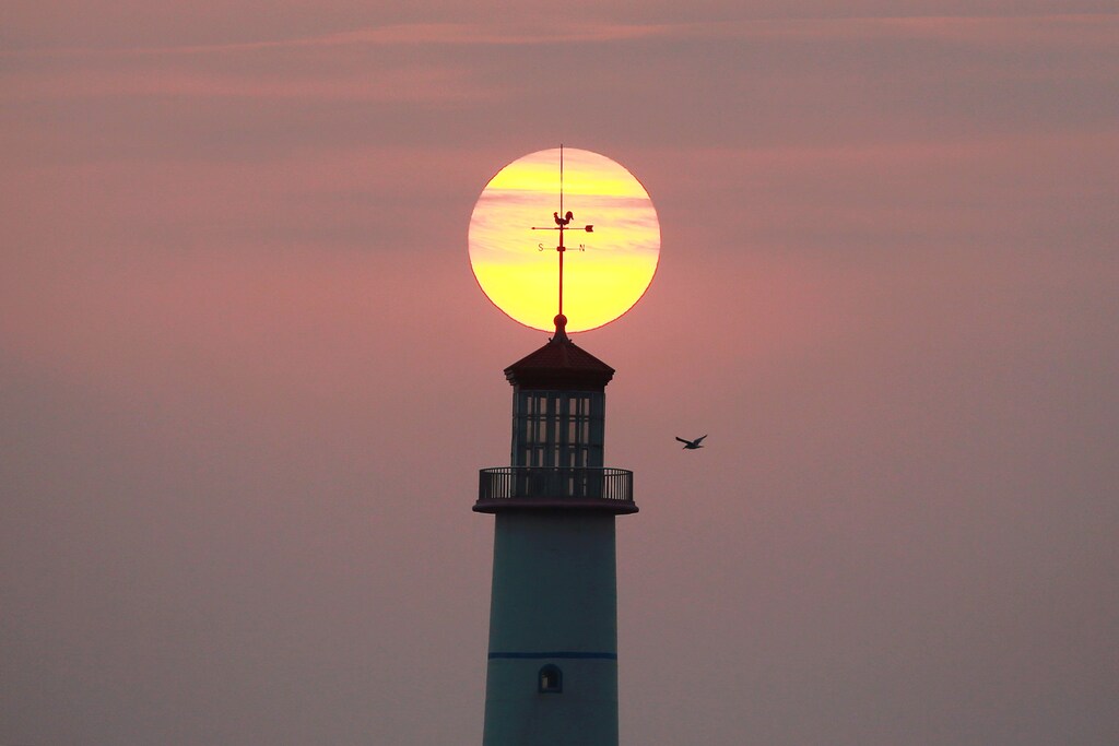 The sun sets behind a lighthouse in Dalian, Liaoning province, China September 29, 2018. Picture taken September 29, 2018. REUTERS/Stringer ATTENTION EDITORS - THIS IMAGE WAS PROVIDED BY A THIRD PARTY. CHINA OUT. - RC136E3704C0