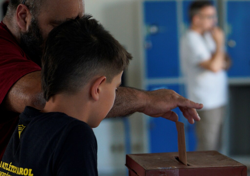 A man casts his vote as a child looks in Uruguay's presidential election run-off between centre-left candidate Yamandu Orsi and ruling conservative coalition candidate Alvaro Delgado, in Montevideo, Uruguay November 24, 2024. REUTERS/Andres Cuenca