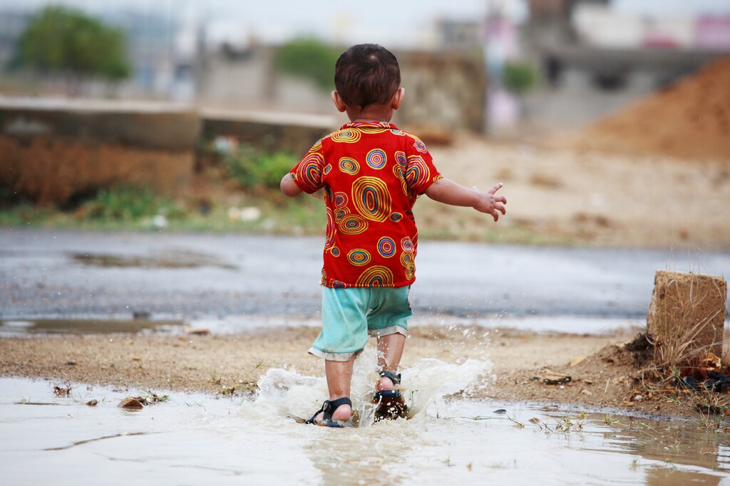 2 year old boy is enjoying and playing in a puddle of stranded rainwater: Effective climate finance with targeted strategies can help alleviate the adverse impacts of extreme heat in South Asia.