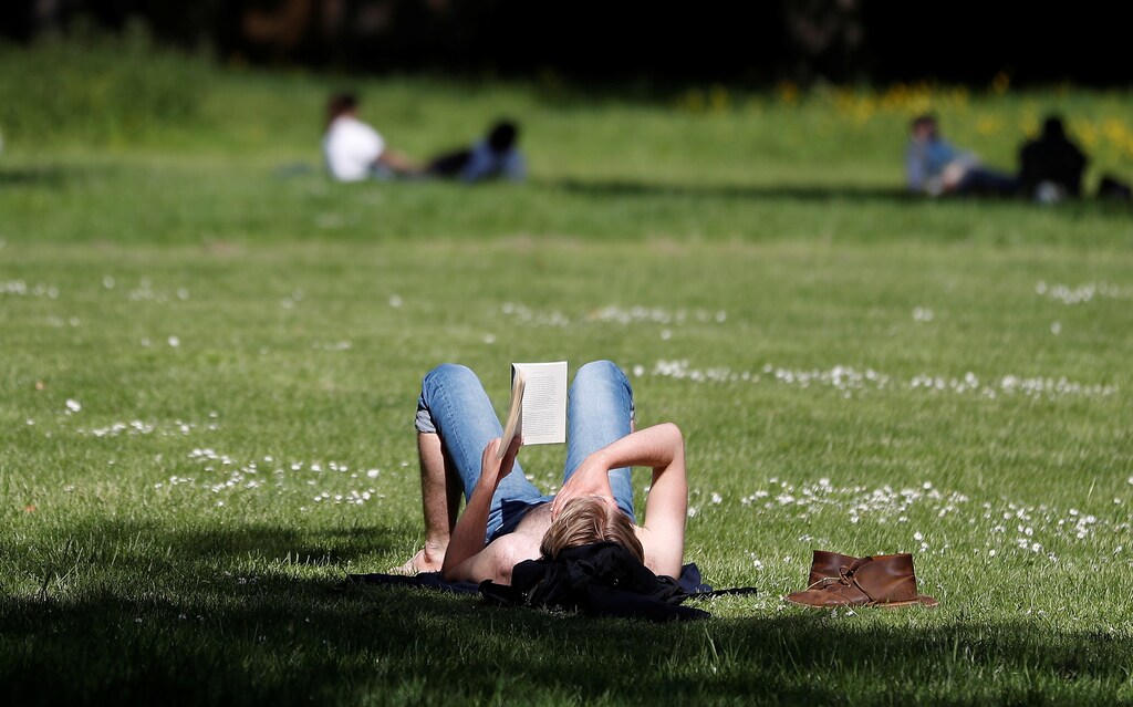A women reads in the sunshine in Hyde Park in London, as a study finds green space can reduce loneliness.
