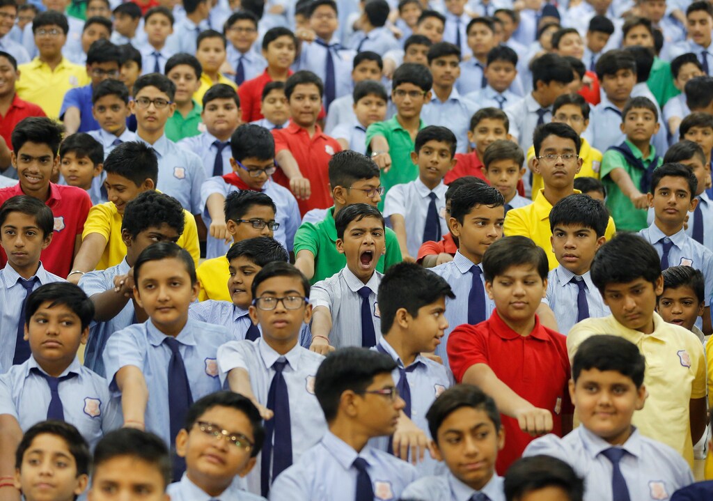A schoolboy yawns as he and other students take an oath inside a school in Ahmedabad, India