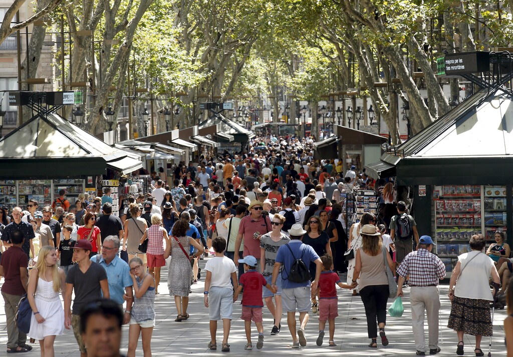 People walk by Las Ramblas in Barcelona, Spain, August 16, 2015. Barcelona's new mayor is picking a fight with home rental websites as she tries to crack down on uncontrolled tourism that she fears could drive out poor residents and spoil the Catalan capital's charm. Picture taken on August 16, 2015. REUTERS/Albert GeaATTENTION EDITORS: SPANISH LAW REQUIRES THAT THE FACES OF MINORS ARE MASKED IN PUBLICATIONS WITHIN SPAIN. - GF10000182225