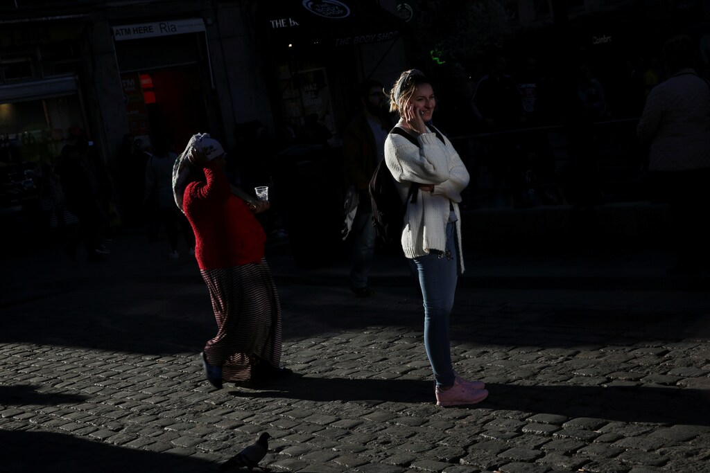 A woman speaks on her cell as another woman walks by asking for money in central Madrid, Spain, March 16, 2017. REUTERS/Susana Vera - RTX31DKP