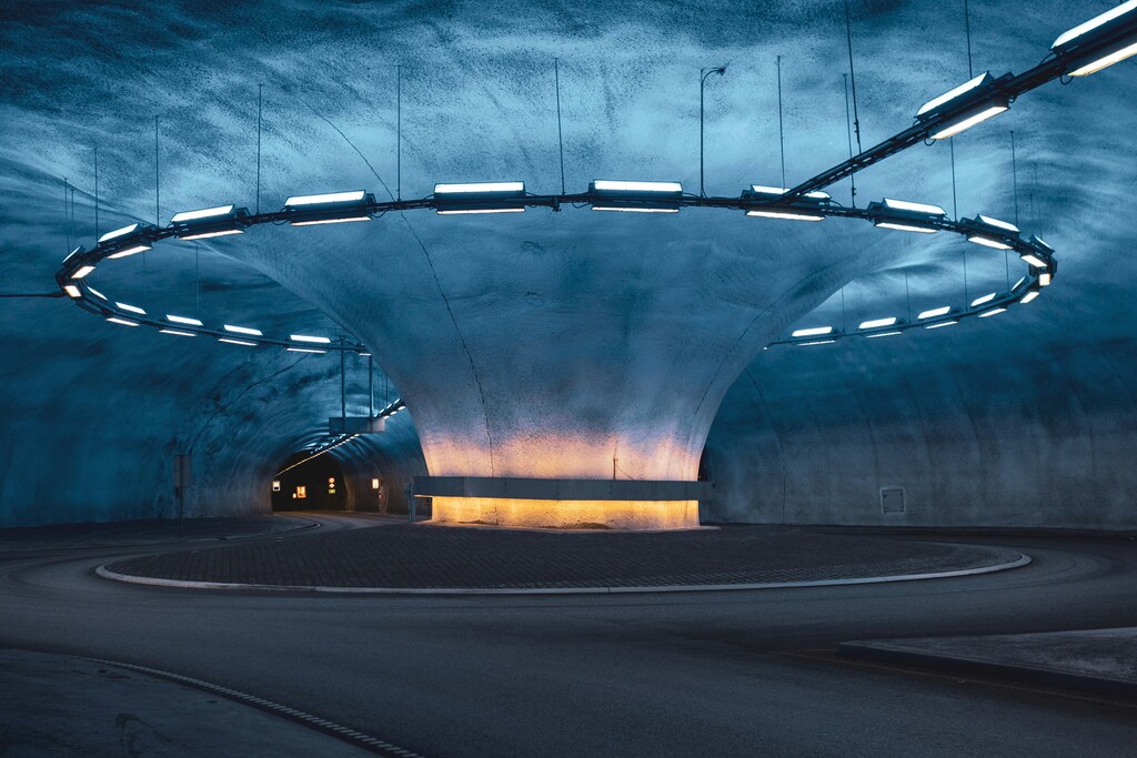 Carretera de hormigón gris en un túnel con pilares circulares y luces amarillas en Noruega: las infraestructuras son tanto un riesgo como una palanca en la transición climática.