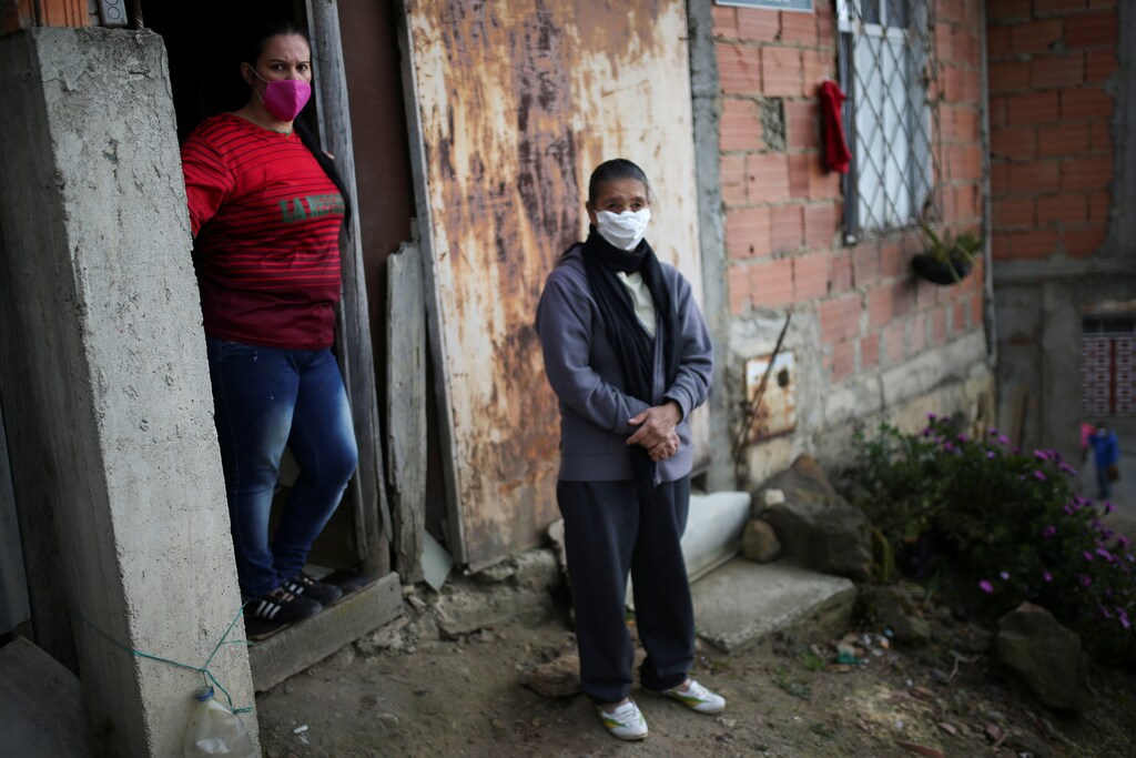 Women wearing face masks wait outside their home for city employees during a day of food aid deliveries, amid the outbreak of the coronavirus disease (COVID-19) in Bogota, Colombia April 21, 2020. REUTERS/Luisa Gonzalez - RC2E9G9KHY8L