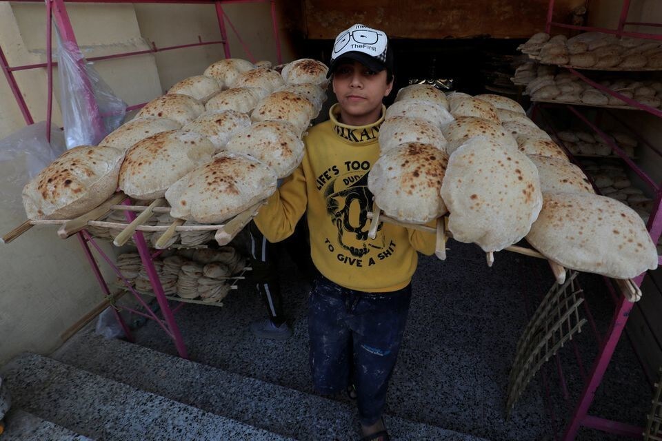 A worker carries loaves of bread at a bakery in Cairo, Egypt, 16 March 2022.