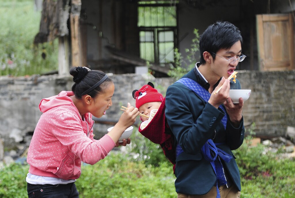 A mother feeds her child, who is being carried by the father, after last Saturday's earthquake hit Lushan county, Ya'an, Sichuan province, April 24, 2013. China has poured resources into Sichuan since the magnitude 6.6 quake hit early on Saturday, including 1 billion yuan ($161.9 million) for disaster relief and compensation. But mountainous terrain and poor infrastructure have made reaching victims difficult. The earthquake has left 196 dead, 21 missing and 11,470 injured, according to Xinhua News Agency. Picture taken April 24, 2013. REUTERS/Stringer (CHINA - Tags: DISASTER ENVIRONMENT TPX IMAGES OF THE DAY) CHINA OUT. NO COMMERCIAL OR EDITORIAL SALES IN CHINA - GM1E94Q11DF01