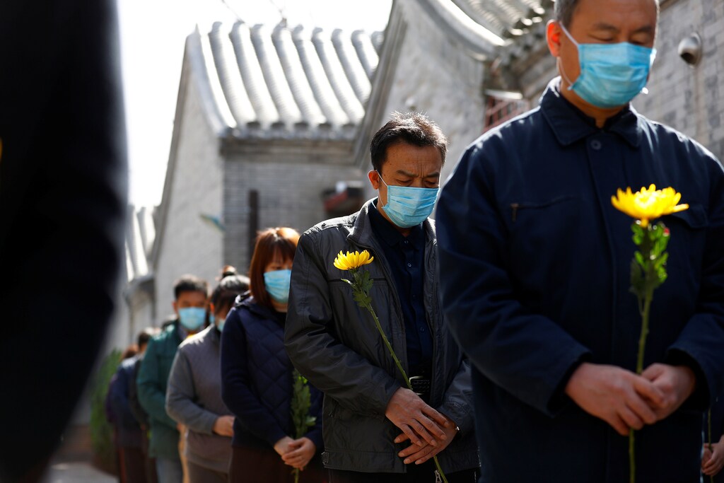 People holding flowers observe a moment of silence at a memorial event in Beijing as China holds a national mourning for those who died of the coronavirus disease (COVID-19), on the Qingming tomb-sweeping festival, April 4, 2020. cnsphoto via REUTERS ATTENTION EDITORS - THIS IMAGE WAS PROVIDED BY A THIRD PARTY. CHINA OUT. - RC2IXF9DZ6NR