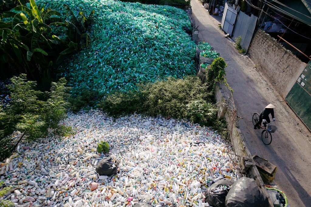 A Vietnamese woman rides past recyclable plastic bottles.