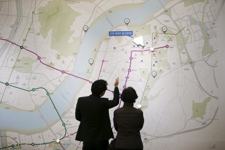 A salesperson (L) talks with a visitor in front of a map showing the location of an apartment complex which is currently under construction at its showroom in Seoul March 18, 2015. While activity is soaring, with the number of transactions at a 7-year high, housing prices are rising at a glacial pace as heavy household debt and a fast-ageing population keep a lid on price growth. To match story SOUTHKOREA-ECONOMY/HOUSING Picture taken on March 18. REUTERS/Kim Hong-Ji