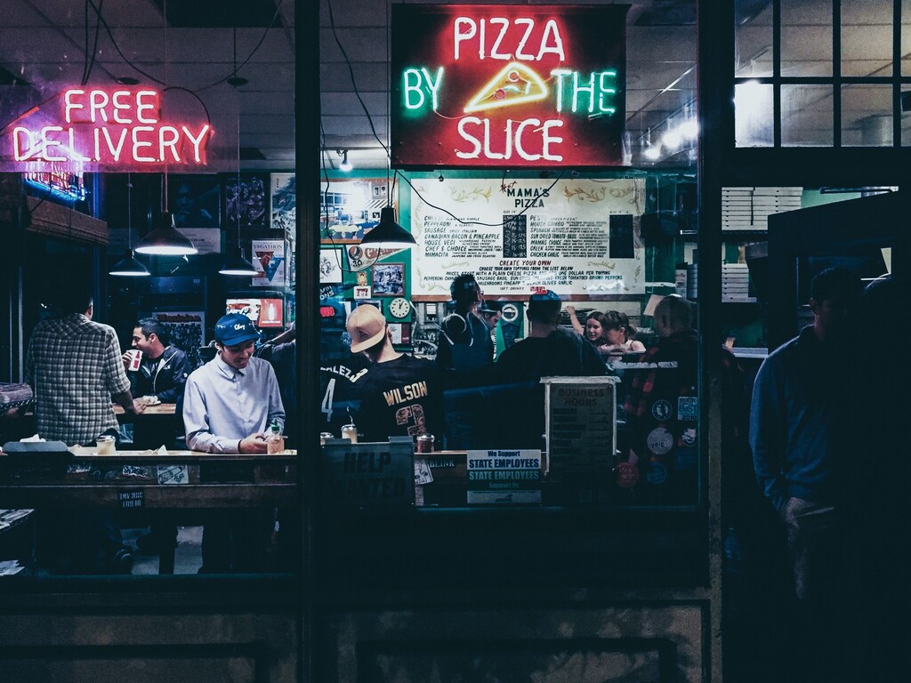 pizza by the slice neon sign hanged on glass panel pizza delivery take out
