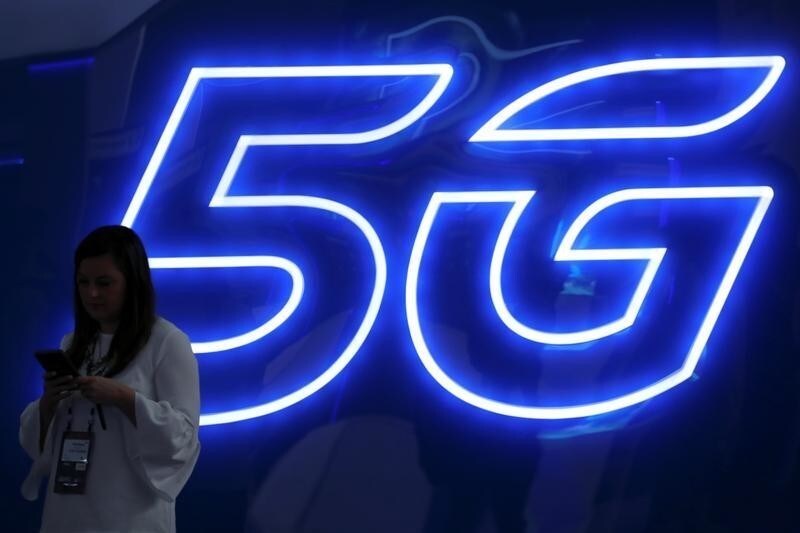 A woman looks at her mobile phone next to a 5G sign at the Mobile World Congress in Barcelona, Spain, February 25, 2019. REUTERS/Sergio Perez - RC13D866DE50