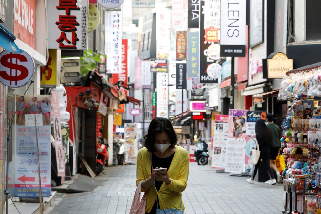 A woman wearing a mask looks at her mobile phone amid social distancing measures to avoid the spread of the coronavirus disease (COVID-19), in Myeongdong shopping district in Seoul, South Korea, May 28, 2020. REUTERS/Kim Hong-Ji - RC2OXG90N3B6
