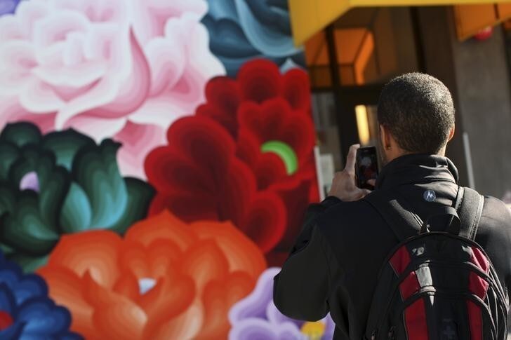 Carl Fisher uses a phone to snap a picture of a mural in the Mission District in San Francisco, California December 18, 2012. Instagram, the popular photo-sharing service owned by Facebook Inc, said Tuesday it has "no plans" to incorporate user photos into ads in response to a growing public outcry over a new privacy policies unveiled this week. REUTERS/Robert Galbraith (UNITED STATES)