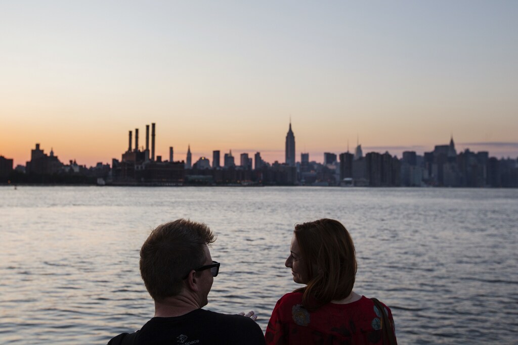 A couple laughs as they watch the sun set behind the skyline of New York, July 16, 2013. The National Weather Service issued heat advisories for dozens of northeastern cities and surrounding areas in Connecticut, Massachusetts, Rhode Island, upstate New York and Long Island. REUTERS/Lucas Jackson (UNITED STATES - Tags: ENVIRONMENT CITYSCAPE) - GM1E97H0PEY01
