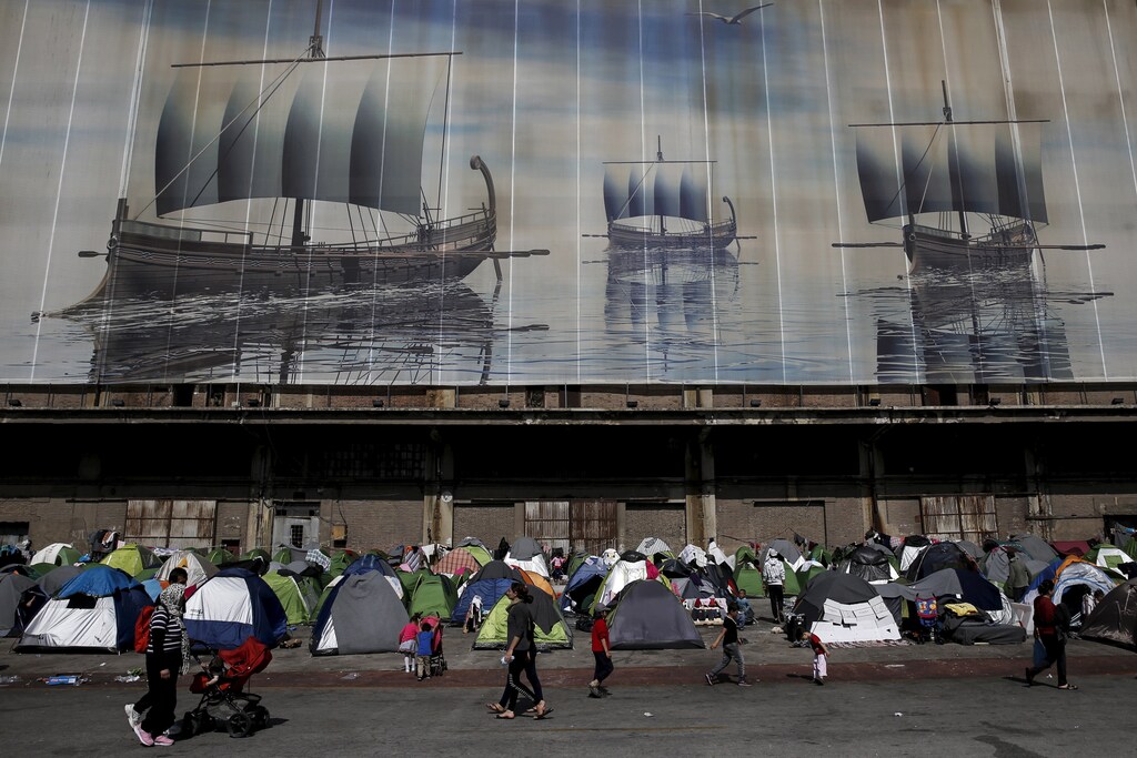 Refugees and migrants walk at a makeshift camp at the port of Piraeus, near Athens, Greece April 6, 2016. REUTERS/Alkis Konstantinidis TPX IMAGES OF THE DAY - GF10000373077