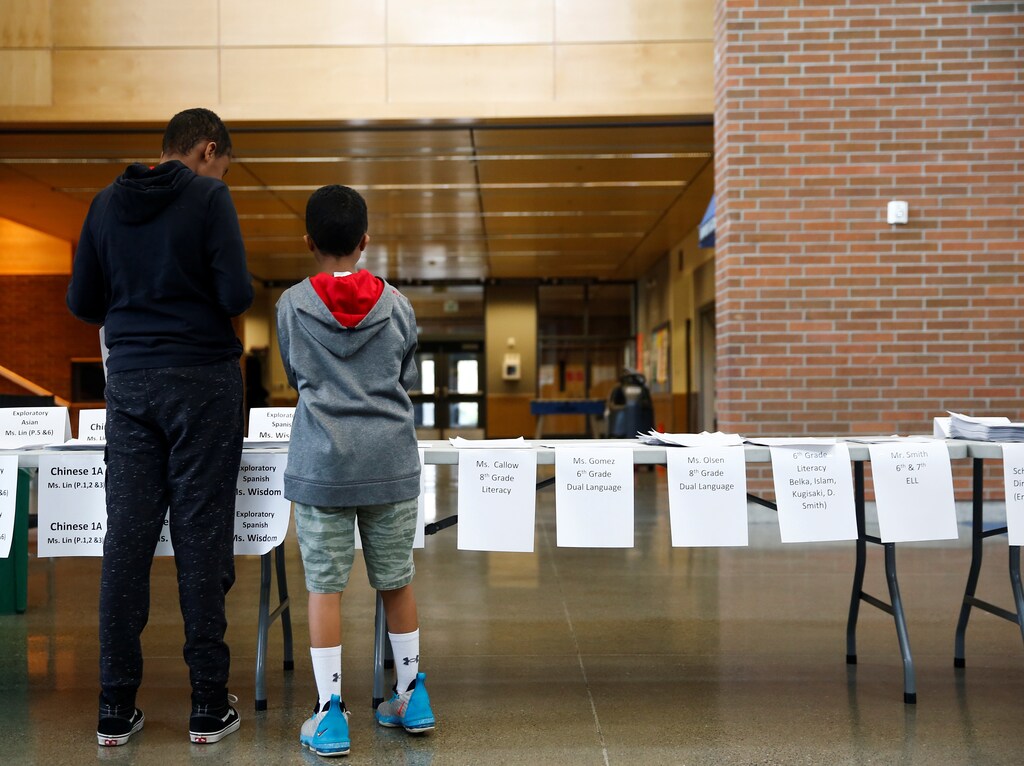 Children pick up curriculum packets for their classes, made available so students won't need a laptop to complete work, at a student meal distribution site in Denny International Middle School during the outbreak of coronavirus disease (COVID-19), in Seattle, Washington, U.S. March 17, 2020. REUTERS/Lindsey Wasson - RC2YLF9IV9CV