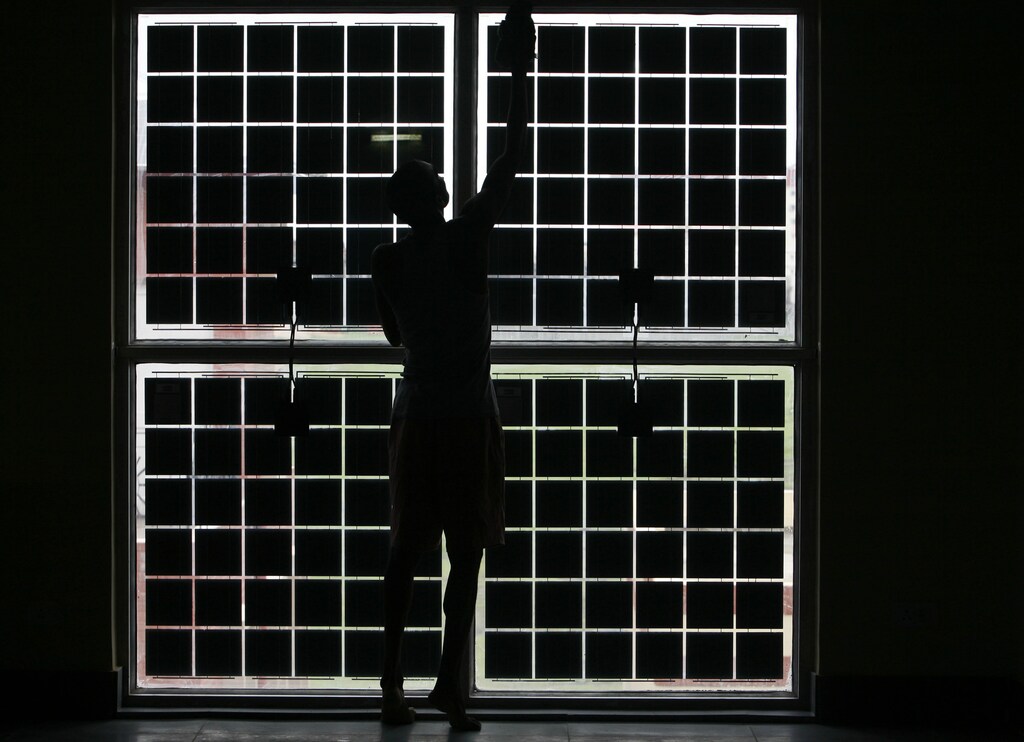 A labourer cleans solar cells placed on a window of a newly constructed solar housing complex in the eastern Indian city of Kolkata July 8, 2008. The buildings are integrated with photovoltaic technology and the complex is constructed by West Bengal Renewable Energy Development Agency. There are 25 houses in the complex and each costs about 4.5 million rupees ($103,950). REUTERS/Parth Sanyal (INDIA) - GM1E4781IM201