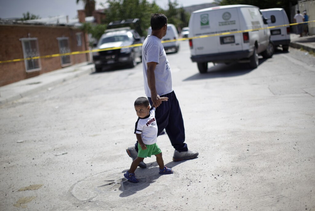 A man and a child walk past a crime scene where five young women had been killed earlier inside a house in Ciudad Juarez August 15, 2010. Neither Mexico's government nor the various independent groups studying organized crime keep track of the number of children dubbed "narco orphans," who have lost one or both parents to the drug war, yet with poor education already holding back Mexico's youth social workers worry about the impact on society of tens of thousands of kids growing up emotionally traumatized. Picture taken August 15, 2010. To match Special Report MEXICO-DRUG/ORPHANS REUTERS/Claudia Daut (MEXICO - Tags: CONFLICT SOCIETY POLITICS) - RTXT4J0