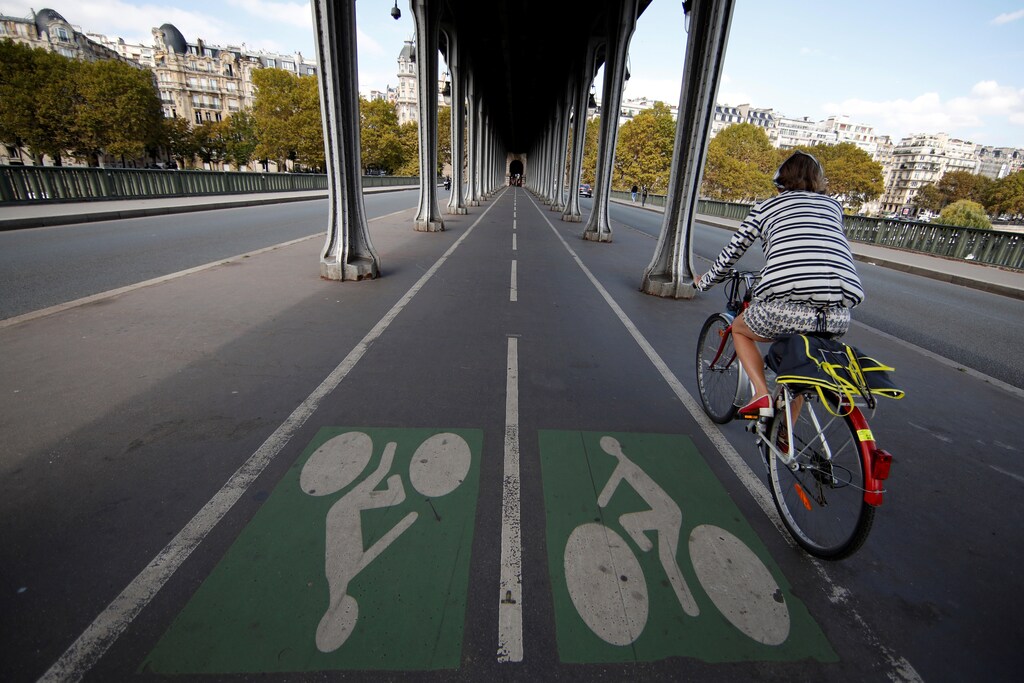 A woman rides a bicycle along a bike path on the Pont de Bir-Hakeim bridge in Paris, France, September 14, 2018. REUTERS/Gonzalo Fuentes - RC168DEE19A0