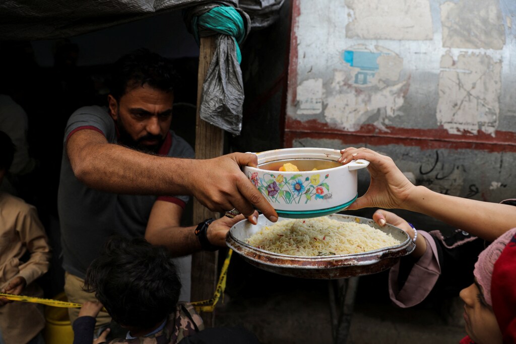 A volunteer gives a meal to a woman at a charity kitchen during Ramadan in Sanaa, Yemen.