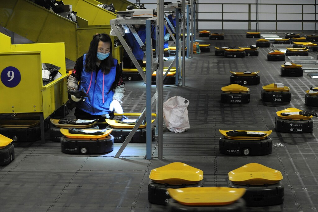 Employees sort parcels with automated guided vehicles (AGVs) at a logistic centre of a postal service a day ahead of the Singles' Day online shopping festival in Nanjing, Jiangsu province, China November 10, 2019. Picture taken November 10, 2019.