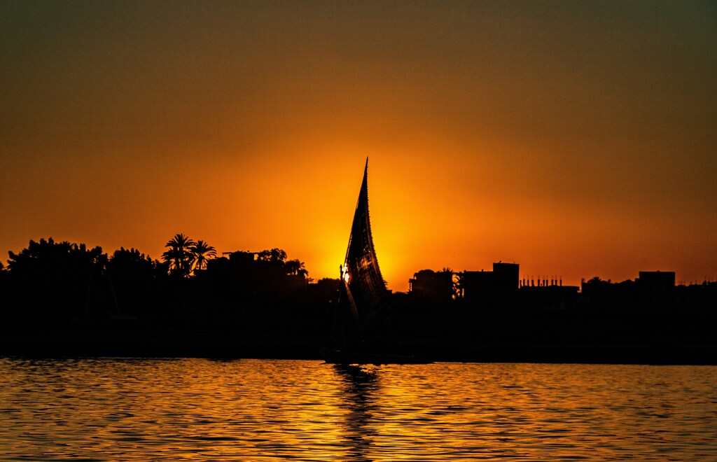 A silhouette image of a sailboat on the nile in Luxor as the sun sets: Egypt empowers innovators to drive sustainable solutions.