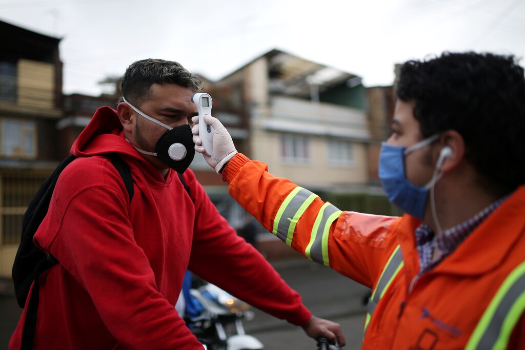 An employee of the construction company Amarilo, wearing a face mask, measures the body temperature of another employee, amid the coronavirus disease (COVID-19) outbreak in Bogota, Colombia May 19, 2020. Picture taken May 19, 2020.