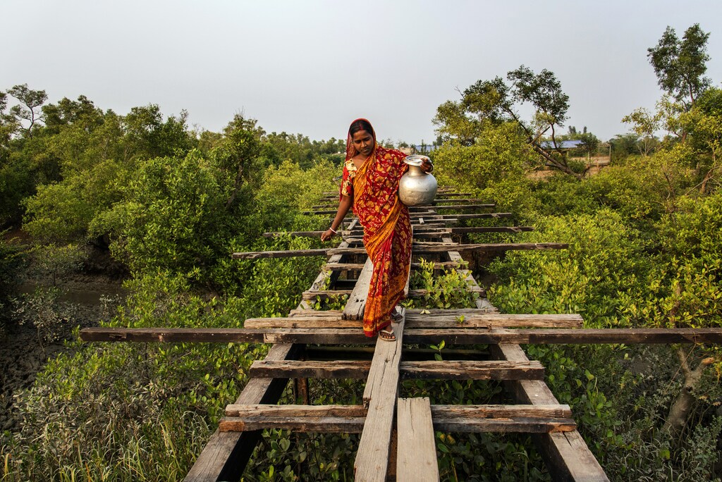 Susmita Mandal Jana, a 22-year-old housewife, who is residing in Madhab Nagar area of Pathar Pratima under South 24 Parganas district of West Bengal, India is crossing a highly risky broken bridge with a big pot to collect the drinking water.