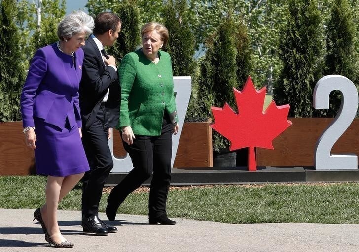 Britain's Prime Minister Theresa May, France's President Emmanuel Macron and Germany's Chancellor Angela Merkel arrive for a family photo at the G7 Summit in the Charlevoix city of La Malbaie, Quebec, Canada, June 8, 2018. REUTERS/Yves Herman