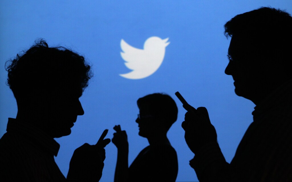 People holding mobile phones are silhouetted against a backdrop projected with the Twitter logo in this illustration picture taken in Warsaw September 27, 2013. Twitter Inc, the eight-year-old online messaging service, gave potential investors their first glance at its financials on Thursday when it publicly filed its IPO documents, setting the stage for one of the most-anticipated debuts in over a year. Picture taken September 27. REUTERS/Kacper Pempel (POLAND - Tags: BUSINESS TELECOMS LOGO) - BM2E9A410KY01